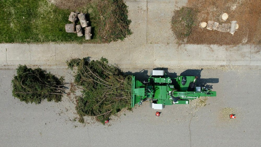 Overhead view of a wood chipper and cut brush at the curb during job cleanup