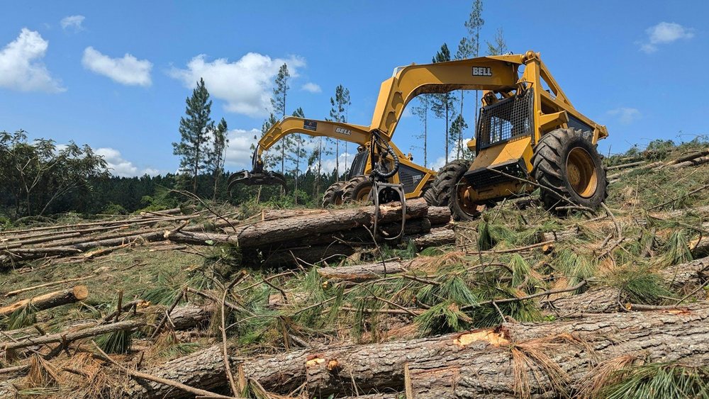 A grapple skidder moving felled logs across a cleared site